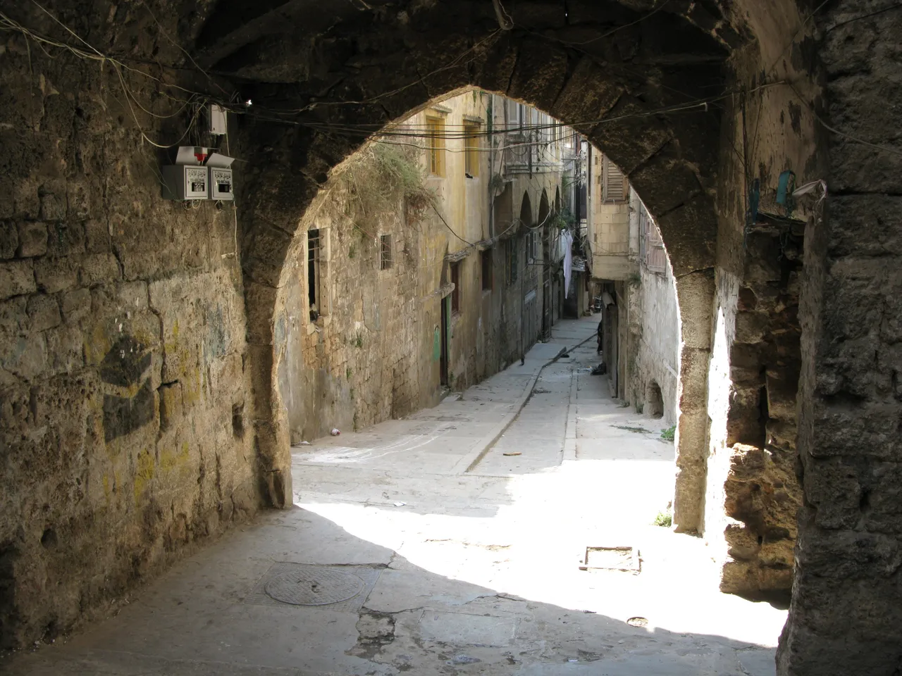 A Mamluk stone arch opening onto a sunlit alley in old Tripoli