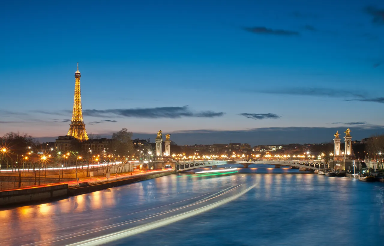 The Eiffel Tower and the Seine at blue hour with boat light trails