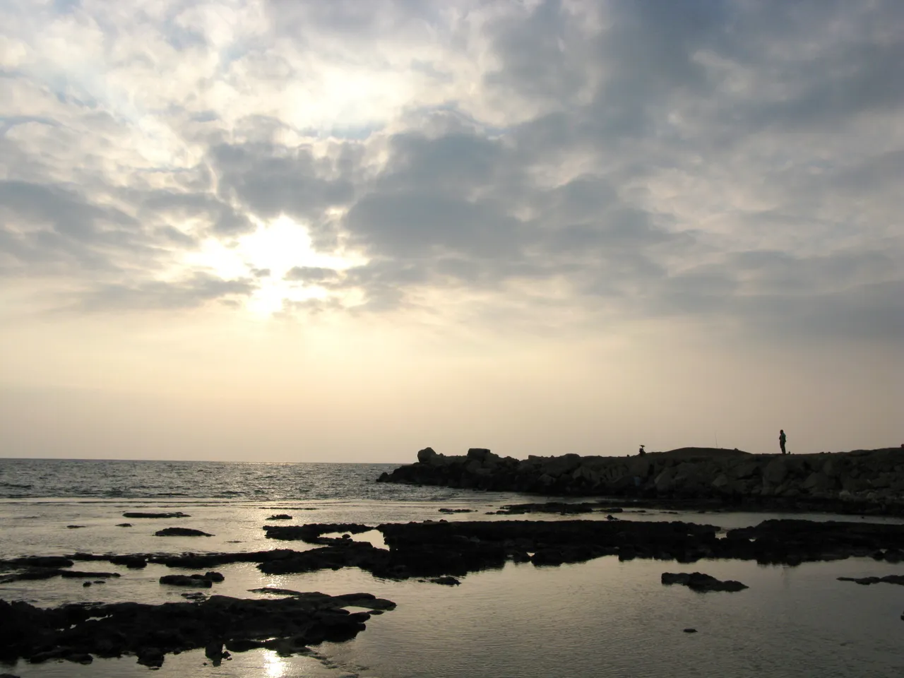 Sun breaking through clouds over the rocky Mediterranean coast at Tripoli